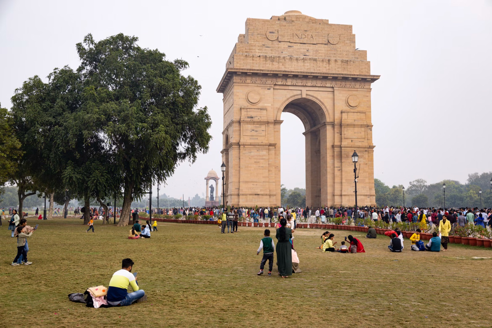 India Gate i New Delhi med folk på græsset foran