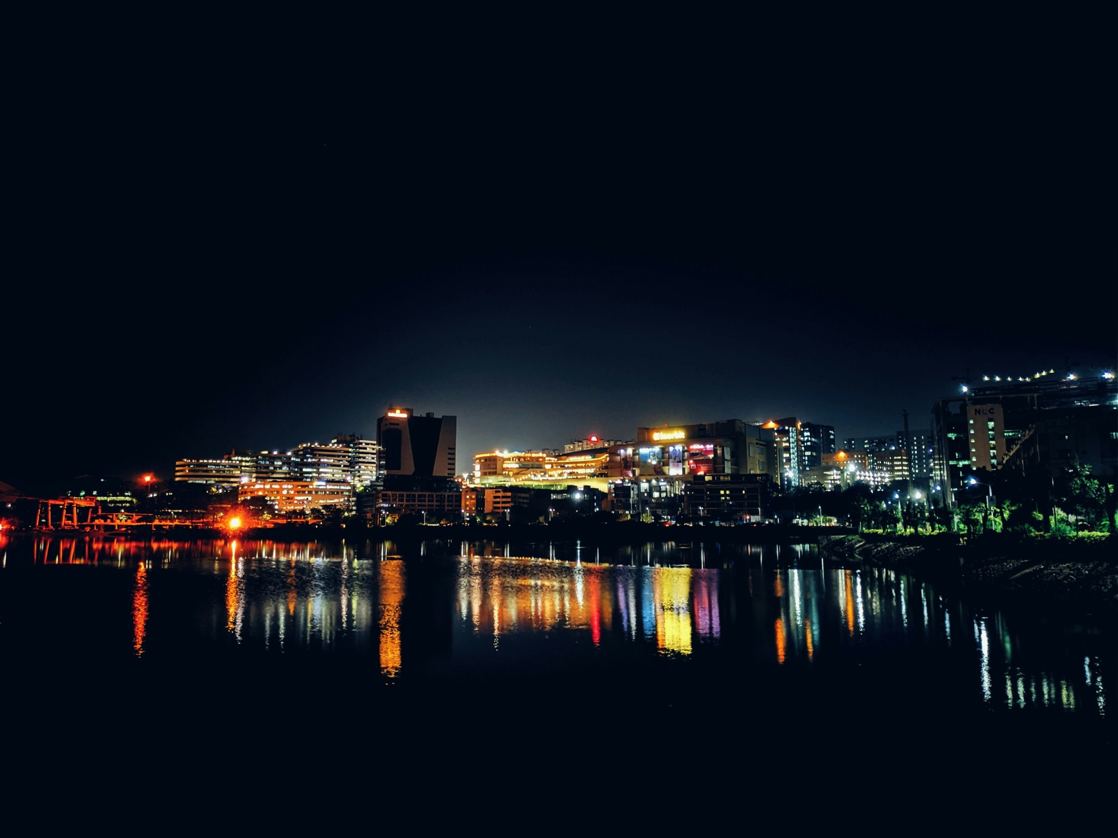 Hyderabads oplyste skyline ved nat, spejlet i vandet