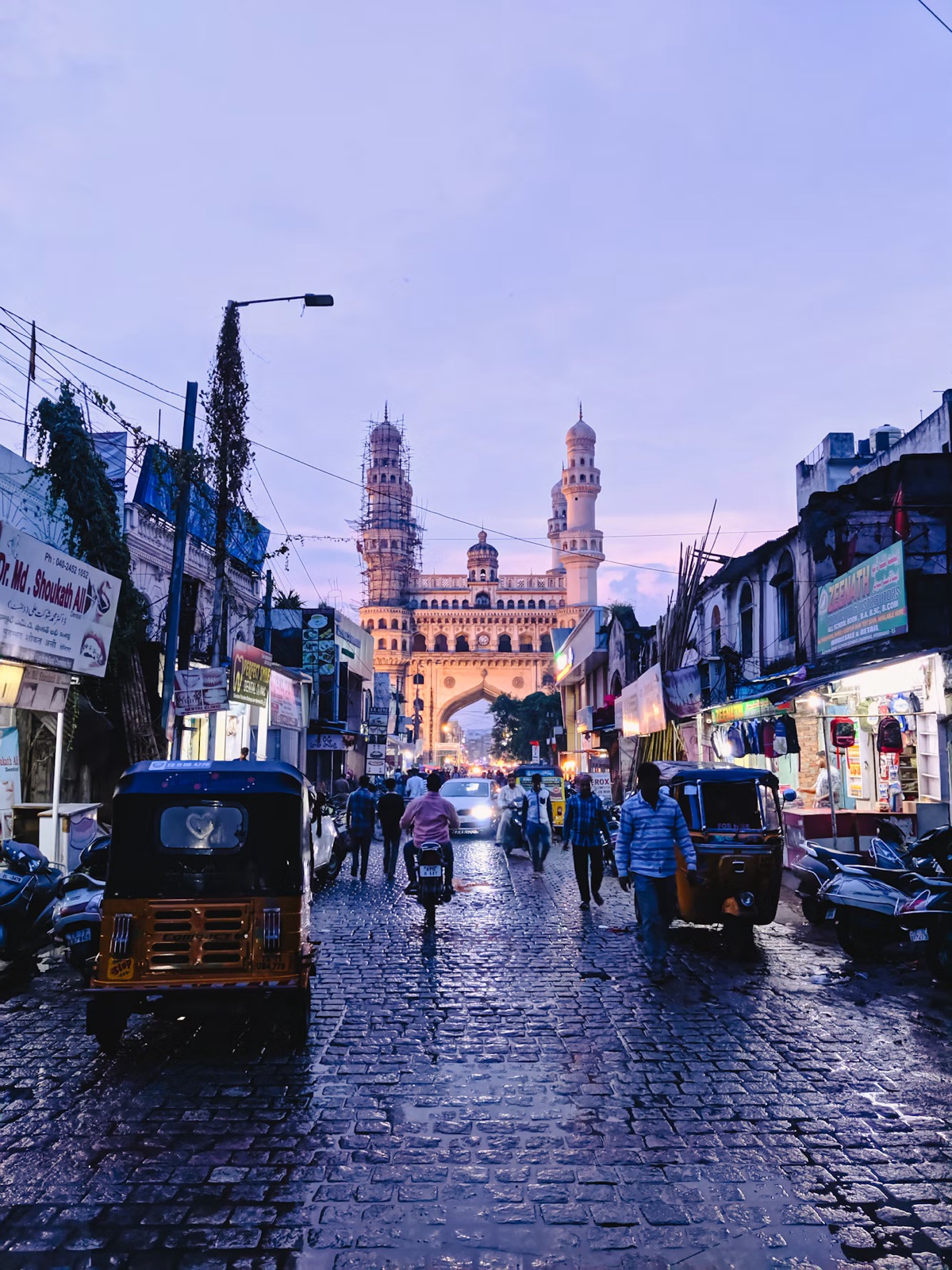 En regnvåd gade i Hyderabad med Charminar i baggrunden